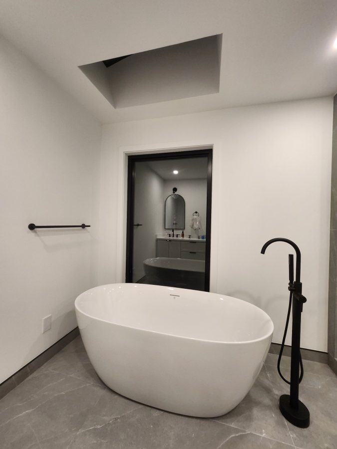 Freestanding oval tub with matte black floor-mounted filler