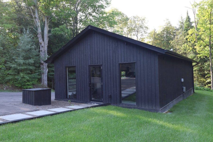 Dark board-and-batten home with lawn and stone path