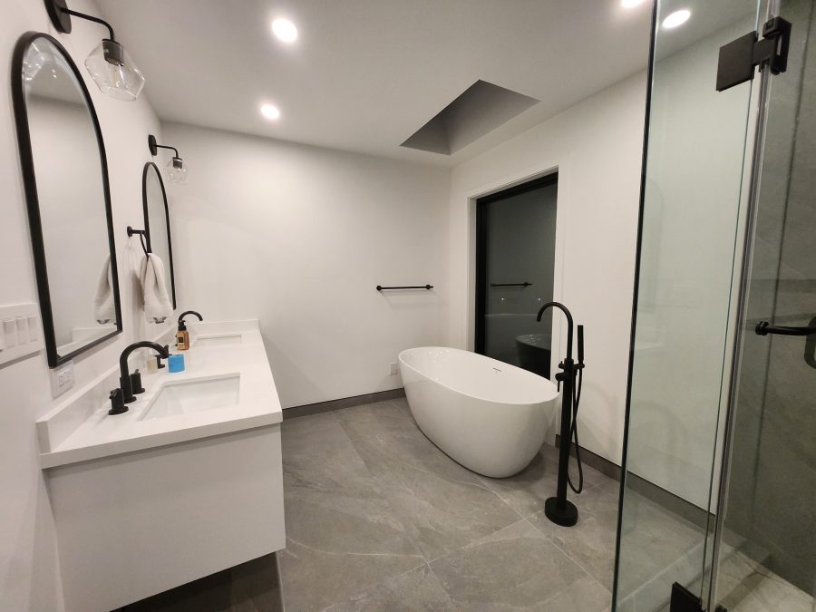 Bathroom with arched mirror, white vanity and freestanding tub