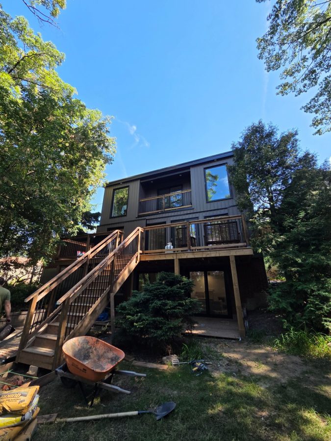Rear of a two-storey home with a new raised deck and stairs